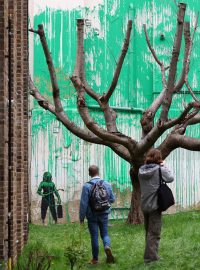 Lidé si prohlížejí novou nástěnnou malbu britského umělce Banksyho na zdi v severním Londýně